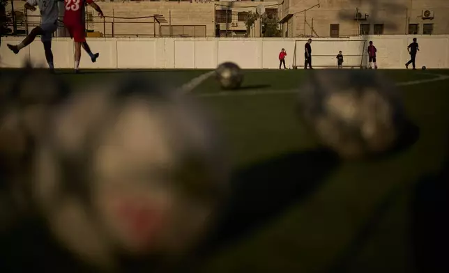 Palestinian children play as youths from a local soccer academy take part in a training session at Jamal Ghanem Stadium in the West Bank city of Tulkarem, Thursday, June 4, 2026. (AP Photo/Leo Correa)