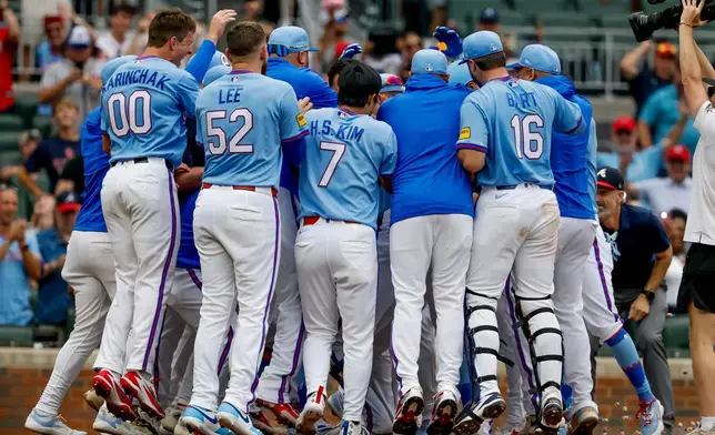 Teammates surround Atlanta Braves' Ozzie Albies at home plate after Albies hit a game-winning two-run home run against the Milwaukee Brewers during the ninth inning of a baseball game, Saturday, June 20, 2026, in Atlanta. (AP Photo/Erik S. Lesser)