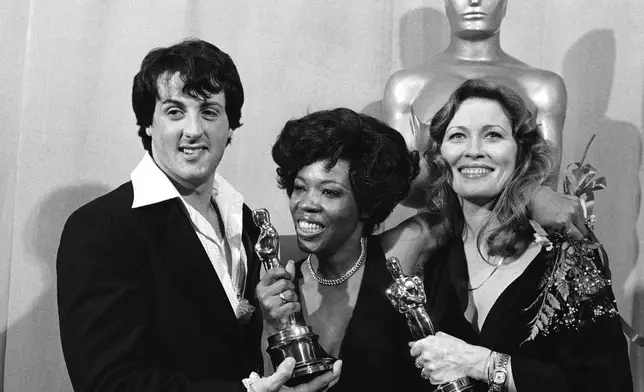 FILE - Actor and screenwriter Sylvester Stallone, left, poses with Eletha Finch, center, widow of actor Peter Finch, and actress Faye Dunaway at the Academy Awards in Los Angeles on March 28, 1977. (AP Photo/File)