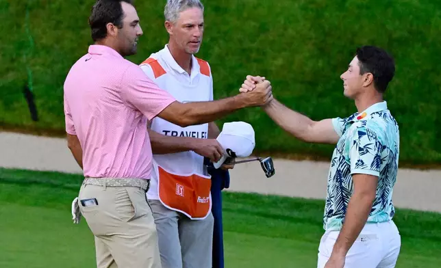 Scottie Scheffler, left, shakes hands with Viktor Hovland, right, of Norway, after finishing tied in the final round of the Travelers Championship golf tournament at TPC River Highlands, Sunday, June 28, 2026, in Cromwell, Conn. (AP Photo/Jessica Hill)