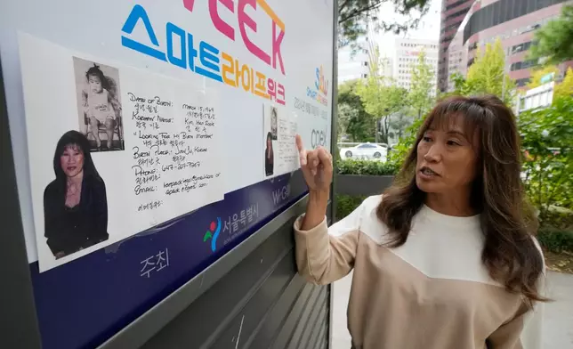 Angela Lee-Pack, a Korean adoptee from Canada, explains flyers with her photos attached to a newspaper stand during an interview with The Associated Press on a street in Seoul, South Korea, on Oct. 21, 2024. (AP Photo/Ahn Young-joon)