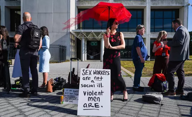 Natile Dilea, a member of a sex-workers rights group, stands in line to enter the Arthur M. Cromarty Criminal Court Complex ahead of a court sentencing for convicted murderer, Rex Heuermann, Wednesday, June 17, 2026, in Suffolk County, New York. (AP Photo/Ryan Murphy)