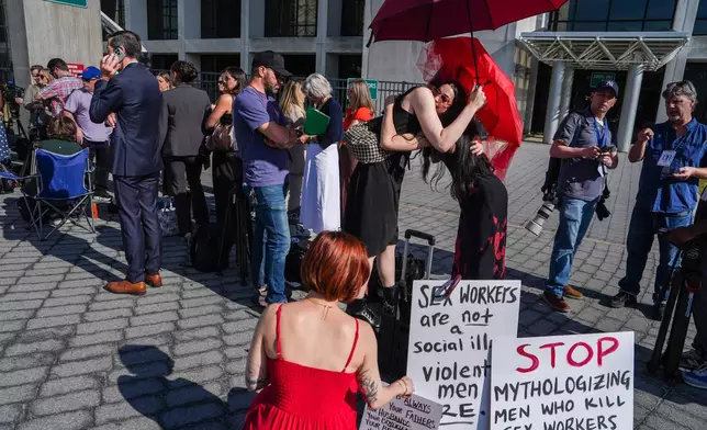 Members of a sex-workers rights group, hug each other while waiting in line to enter the Arthur M. Cromarty Criminal Court Complex ahead of a court sentencing for convicted murderer, Rex Heuermann, Wednesday, June 17, 2026, in Suffolk County, New York. (AP Photo/Ryan Murphy)