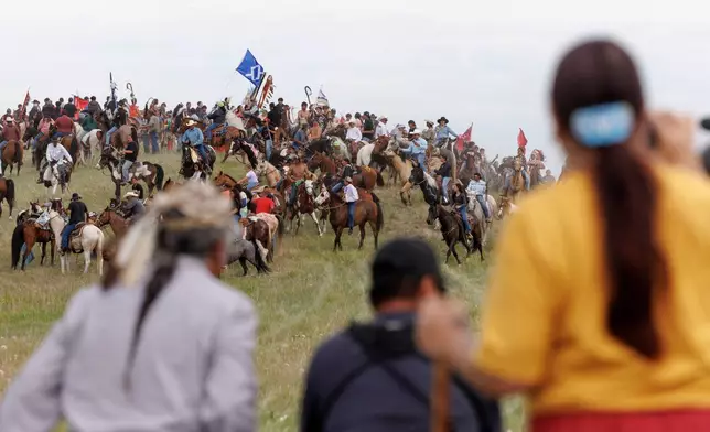 Spectators watch the annual horse charging event during festivities to commemorate the 150th anniversary of the Battle of the Little Bighorn in Crow Agency, Mont., on Thursday, June 25, 2026. (AP Photo/Tailyr Irvine)