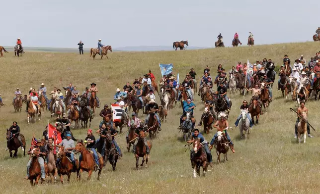 Riders charge toward spectators during festivities to commemorate the 150th anniversary of the Battle of the Little Bighorn in Crow Agency, Mont., on Thursday, June 25, 2026. (AP Photo/Tailyr Irvine)