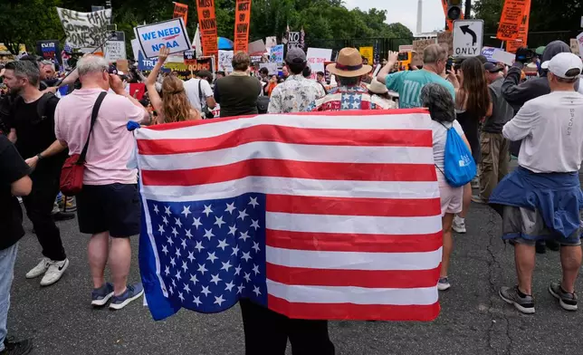 FILE - A demonstrator carries an American flag upside-down near the White House during a protest taking place on the day of a military parade commemorating the Army's 250th anniversary, coinciding with President Donald Trump's 79th birthday, June 14, 2025, in Washington. (AP Photo/Alex Brandon, File)