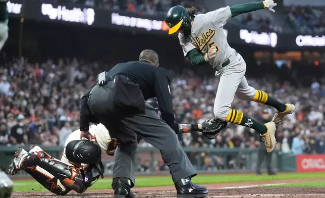 Umpire Ramon de Jesus, middle, watches as San Francisco Giants catcher Eric Haase, bottom, reaches to tag out Athletics' Jacob Wilson, top, during the fifth inning of a baseball game Wednesday, June 24, 2026, in San Francisco. (AP Photo/Jeff Chiu)