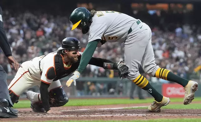 San Francisco Giants catcher Eric Haase, left, reaches to tag out Athletics' Jacob Wilson during the fifth inning of a baseball game Wednesday, June 24, 2026, in San Francisco. (AP Photo/Jeff Chiu)