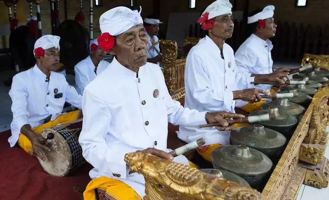 Balinese men plays traditional musical instruments during the performance of the sacred Rejang dance during Kuningan holiday, which marks the end of the 10-day Galungan festival celebrating the victory of good over evil, in Karangasem, Bali, Indonesia, Saturday, June 27, 2026. (AP Photo/Firdia Lisnawati)