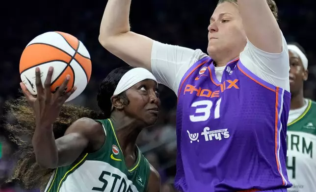 Seattle Storm guard Flau'jae Johnson (4) drives to the basket as Phoenix Mercury center Kyara Linskens (31) defends during the first half of a WNBA basketball game, Saturday, June 20, 2026, in Phoenix. (AP Photo/Ross D. Franklin)