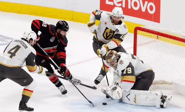 Carolina Hurricanes' Jordan Martinook (48) reaches for a puck near the goal between Vegas Golden Knights' Rasmus Andersson (4), Noah Hanifin (15), and Vegas goaltender Carter Hart (79) during the first period of Game 2 of the NHL hockey Stanley Cup Final series in Raleigh, N.C., Thursday, June 4, 2026. (AP Photo/Ben McKeown)