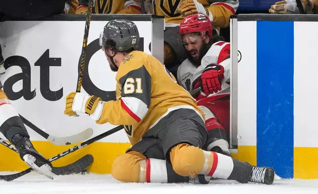 Carolina Hurricanes defenseman Jalen Chatfield, right, is checked through a a doorway by Vegas Golden Knights right wing Mark Stone during overtime in Game 3 of the NHL hockey Stanley Cup Final series Saturday, June 6, 2026, in Las Vegas. (AP Photo/John Locher)
