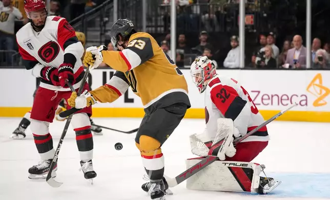 Vegas Golden Knights right wing Mitch Marner, center, attempts to tip the puck past Carolina Hurricanes goaltender Brandon Bussi, right, as defenseman K'andre Miller defends during overtime in Game 3 of the NHL hockey Stanley Cup Final series Saturday, June 6, 2026, in Las Vegas. (AP Photo/John Locher)
