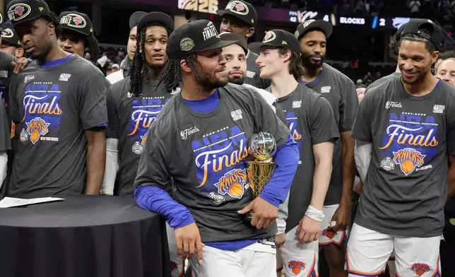 New York Knicks guard Jalen Brunson, center, holds the MVP trophy after Game 4 in the Eastern Conference finals NBA basketball playoffs series against the Cleveland Cavaliers in Cleveland, Monday, May 25, 2026. (AP Photo/Sue Ogrocki)