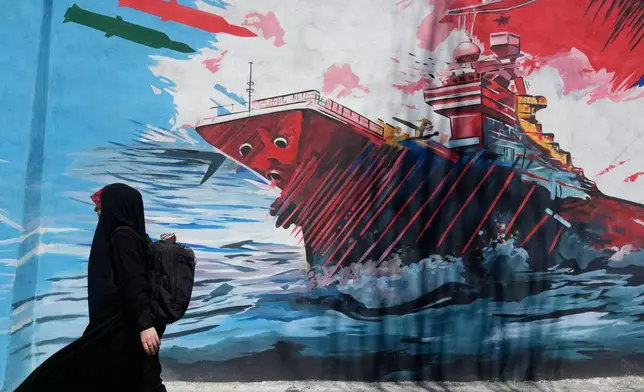 A woman walks past a mural depicting a U.S. aircraft carrier under missile attack in downtown Tehran, Iran, Monday, June 8, 2026. (AP Photo/Vahid Salemi)