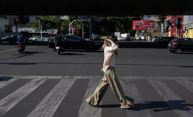 A woman adjusts her headscarf as she crosses an intersection in northern Tehran, Wednesday, June 10, 2026. (AP Photo/Vahid Salemi)