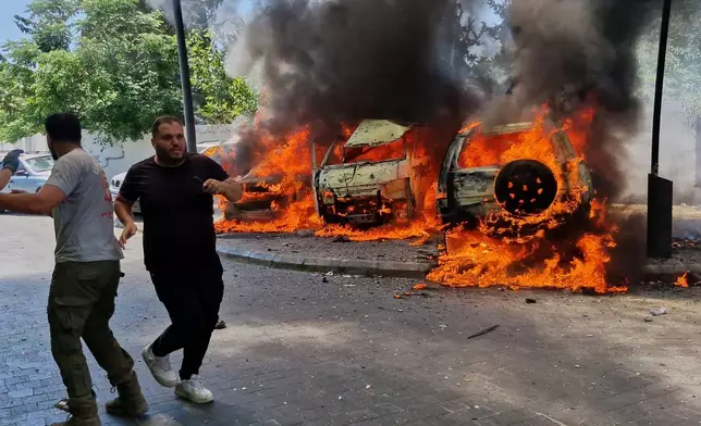 A man runs past burning cars following an Israeli airstrike in the southern port city of Sidon, Lebanon, Wednesday, June 10, 2026. (AP Photo/Mohammed Zaatari)