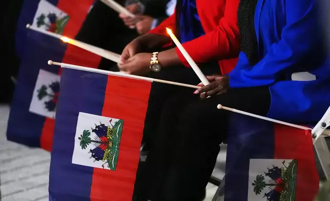 FILE - People hold Haitian flags and candles during a vigil at the Little Haiti Cultural Complex after a federal judge blocked the Trump administration from ending temporary immigration status, or TPS, for Haitians, Feb. 3, 2026, in North Miami. (AP Photo/Lynne Sladky, File)