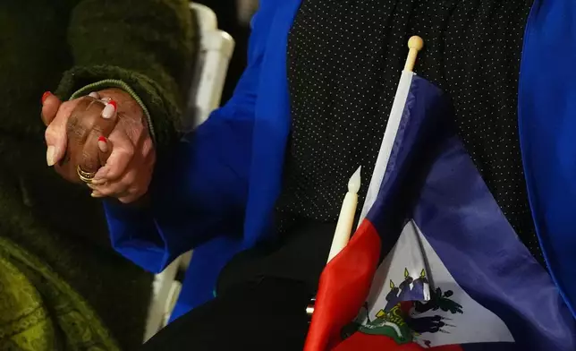 FILE - People hold hands and a Haitian flag during a vigil at the Little Haiti Cultural Complex after a federal judge blocked the Trump administration from ending temporary immigration status, or TPS, for Haitians, Feb. 3, 2026, in North Miami. (AP Photo/Lynne Sladky, File)
