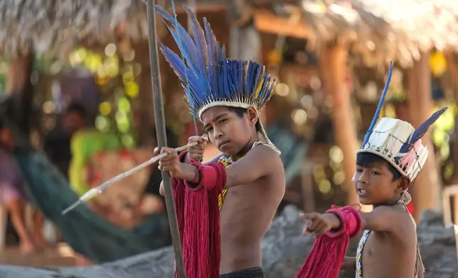 Cousins Gustavo Javae, left, and Gael Javae, from the Javae Indigenous group, play with a bow and arrow at the Txuiri village on Bananal Island in Formoso do Araguaia, Tocantins state, Brazil, Thursday, May 21, 2026. (AP Photo/Andre Penner)