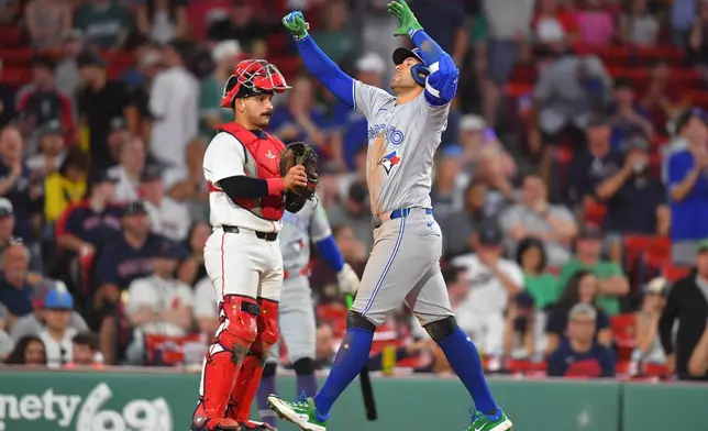 Toronto Blue Jays' George Springer, right, celebrates in front of Boston Red Sox catcher Mickey Gasper, left, as he arrives home after hitting a two-run home run in the ninth inning of a baseball game, Tuesday, June 16, 2026, in Boston. (AP Photo/Steven Senne)