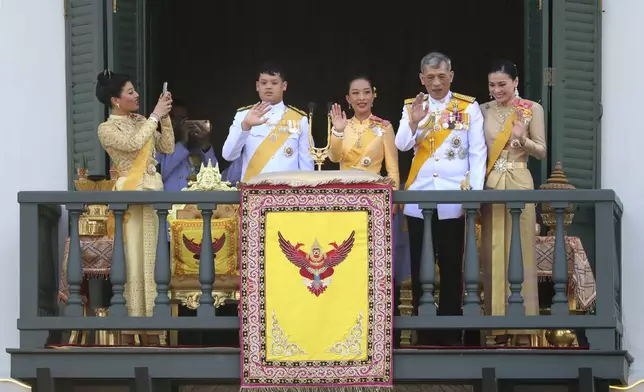 FILE - Princess Sirivannavari Nariratana, left, daughter of King Maha Vajiralongkorn, second right, and Queen Suthida, right, takes a photo of her royal family members also including Prince Dipangkorn Rasmijoti, second left, and Princess Bajrakitiyabha, as they wave towards audience members from the balcony of Suddhaisavarya Prasad Hall in the Grand Palace during the coronation ceremony, May 6, 2019, in Bangkok, Thailand. (AP Photo/Sakchai Lalit, File)