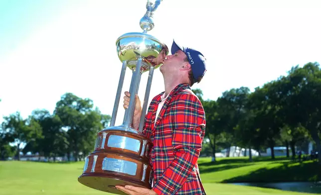 Russell Henley kisses the winner's trophy after the final round of the Charles Schwab Challenge golf tournament at Colonial Country Club in Fort Worth, Texas, Sunday, May 31, 2026. (AP Photo/LM Otero)