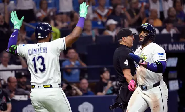 Tampa Bay Rays' Junior Caminero (13) and Yandy Díaz celebrate after Diaz scores on a double by Jonathan Aranda, not pictured, during the seventh inning of a baseball game against the Arizona Diamondbacks Friday, June 26, 2026, in St. Petersburg, Fla. (AP Photo/Jason Behnken)