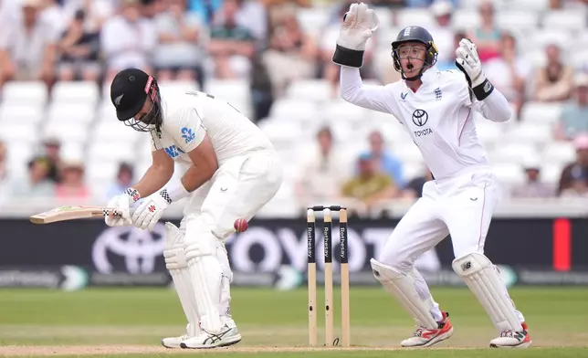England's Jamie Smith, right, reacts as New Zealand's Daryl Mitchell is struck by the ball on day four of the Third Test cricket match between England and New Zealand, in Nottingham, England, Sunday June 28, 2026. (Joe Giddens/PA via AP)
