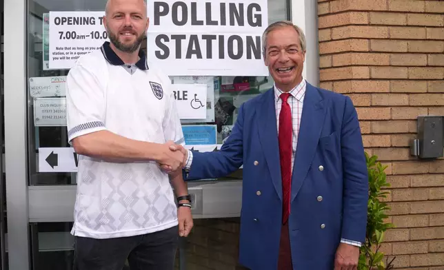 Britain's Reform Party leader Nigel Farage and local candidate Rob Kenyon ashake hands at a polling station during the by-election in Makerfield, England, Thursday, June 18, 2026.(AP Photo/Jon Super)
