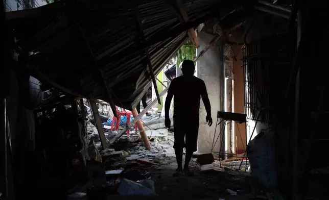 A resident walks past debris from damaged houses following an earthquake in General Santos, Philippines Tuesday, June 9, 2026. (AP Photo/Basilio Sepe)
