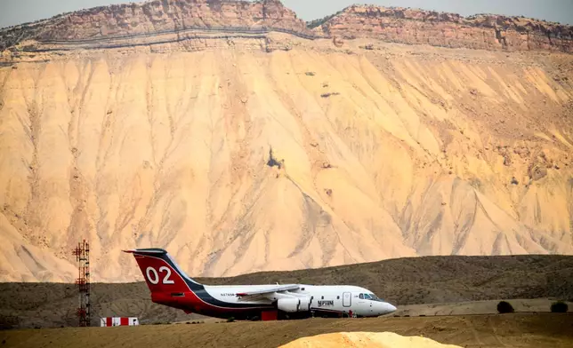 A firefighting aircraft rests on the tarmac at Grand Junction Regional Airport in Grand Junction, Colo., as the Snyder Fire burns nearby on Sunday, June 28, 2026. (AP Photo/Noah Berger)