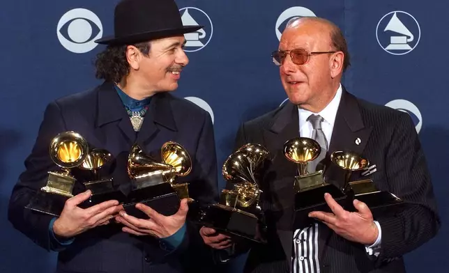 FILE - Carlos Santana, left, and producer Clive Davis pose with their Grammys at the 42nd Grammy Awards in Los Angeles, on Feb. 23, 2000. (AP Photo/Reed Saxon, File)