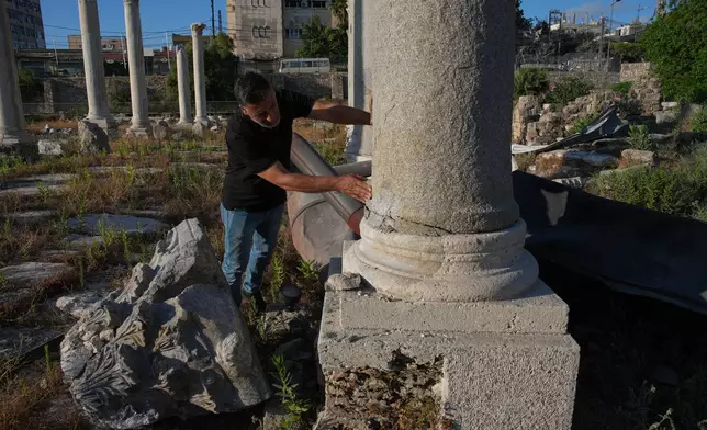 Adnan Istanbuli, an employee at the Directorate General of Antiquities, inspects a Roman-era column after part of its capital was knocked off and fell to the ground at an archaeological site lightly damaged in an Israeli strike nearby last week, in the southern port city of Tyre, Lebanon, Thursday, June 18, 2026. (AP Photo/Hassan Ammar)