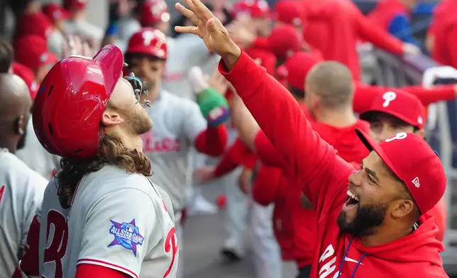 Philadelphia Phillies' Alec Bohm has seeds dropped into his mouth as he celebrates in the dugout after hitting a three-run home run off Toronto Blue Jays pitcher Max Scherzer during the third inning of a baseball game in Toronto on Wednesday, June 10, 2026. (Chris Young/The Canadian Press via AP)