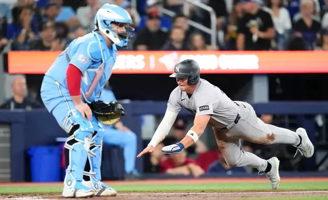 New York Yankees' Max Schuemann reaches home to score in front of Toronto Blue Jays catcher Alejandro Kirk after an RBI single from Anthony Volpe during the second inning of a baseball game in Toronto on Sunday June 14, 2026. (Chris Young/The Canadian Press via AP)