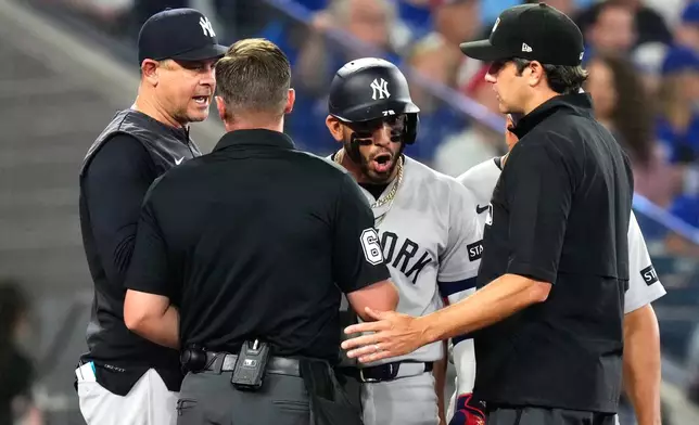 New York Yankees' José Caballero, third from left, and manager Aaron Boone, left, exchange views with home plate umpire Steven Jaschinski, second from left, and second base umpire John Tumpane, front right, during the sixth inning of a baseball game against the Toronto Blue Jays in Toronto, Sunday June 14, 2026. (Chris Young/The Canadian Press via AP)