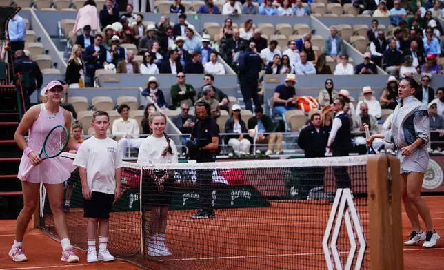 Russia's Mirra Andreeva poses with children while Ukraine's Marta Kostyuk refused to join before the semifinal tennis match at the French Open in Paris, Thursday, June 4, 2026. (AP Photo/Christophe Ena)