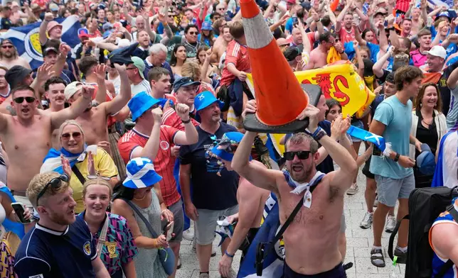 A Scotland soccer fan dances with a traffic cone as part of the Tartan Army march outside of loanDepot park before a baseball game between the Miami Marlins and the Texas Rangers, Monday, June 22, 2026, in Miami. (AP Photo/Lynne Sladky)