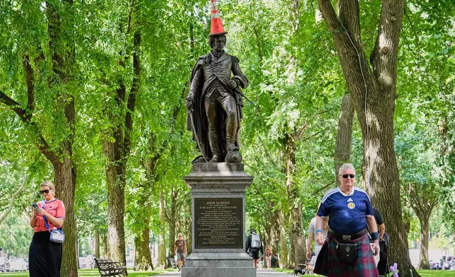 Scottish fans passing a statue of the revolutionary John Glover, humorously decorated with a traffic cone, in a park in Boston, Mass., ahead of the World Cup Group C soccer match between Scotland and Morocco, Friday, June 19, 2026. (AP Photo/Martin Meissner)