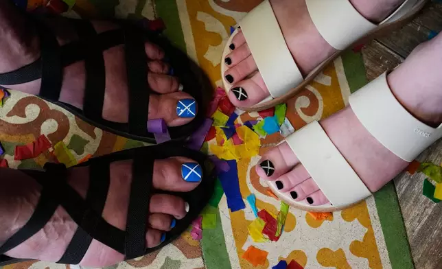 A mother and daughter show support for Scotland in the World Cup with their toenail polish as soccer fans with the Tartan Army gather in the Ball and Chain music bar in Miami before marching to a Miami Marlins against the Texas Rangers baseball game Monday, June 22, 2026. (AP Photo/Rebecca Blackwell)