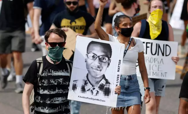 FILE - A demonstrator carries an image of Elijah McClain during a rally and march, June 27, 2020, in Aurora, Colo. Two paramedics were convicted Friday, Dec. 22, 2023, in the 2019 killing of McClain, who they injected with an overdose of the sedative ketamine after police put him in a neck hold. (AP Photo/David Zalubowski, File)