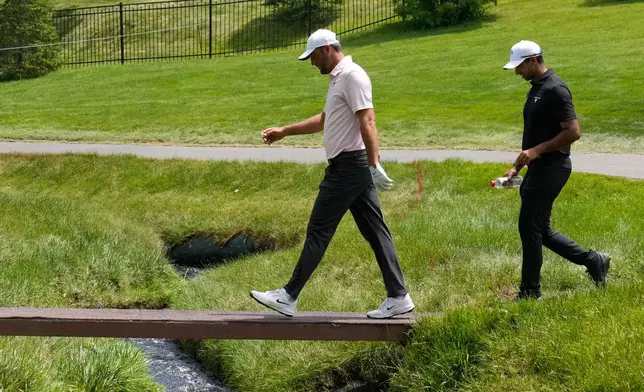 Scottie Scheffler, left, and Aaron Rai, of England, right, walk across a bridge on the second fairway during the first round of the Memorial golf tournament in Dublin, Ohio, Thursday, June 4, 2026. (AP Photo/Sue Ogrocki)