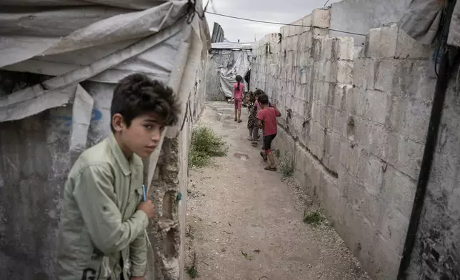 FILE - Children play through al-Karama camp, established in the early years of the Syrian conflict and built from scratch with light-brick structures covered with fabric to house internally displaced Syrians near the village of Atmeh, Idlib province, Syria, May 19, 2026. (AP Photo/Omar Albam, File)