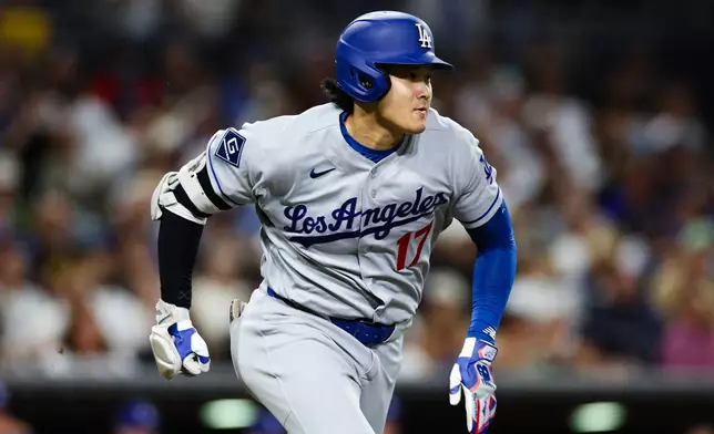 Los Angeles Dodgers' Shohei Ohtani runs to first after hitting a ground ball to San Diego Padres' Ty France for an out in the sixth inning of a baseball game Friday, June 26, 2026, in San Diego. (AP Photo/Derrick Tuskan)