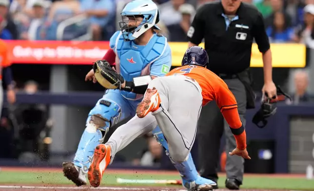 Houston Astros' Jeremy Pena (3) dives into home plate to score in front of Toronto Blue Jays catcher Alejandro Kirk (30) during the first inning of a baseball game in Toronto on Wednesday, June 24, 2026. (Chris Young/The Canadian Press via AP)