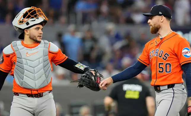 Houston Astros catcher Yainer Diaz (21) congratulated Astros pitcher Mike Burrows (50) after Toronto Blue Jays Vladimir Guerrero Jr. lined out to end sixth inning of a baseball game in Toronto on Wednesday, June 24, 2026. (Chris Young/The Canadian Press via AP)