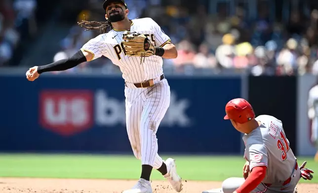 San Diego Padres second baseman Fernando Tatis Jr. throws past Cincinnati Reds' Nathaniel Lowe (31) as he tries to turn a double play during the sixth inning of a baseball game, Wednesday, June 10, 2026, in San Diego. (AP Photo/Denis Poroy)