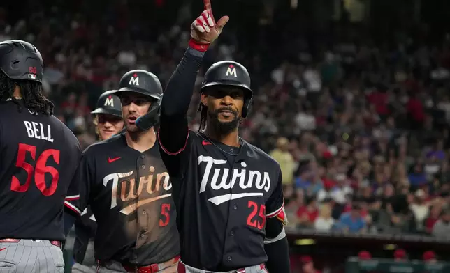 Minnesota Twins' Byron Buxton (25) celebrates after hitting a grand slam with teammates Josh Bell (56) and Ryan Kreidler (5) in the fifth inning of a baseball game against Arizona Diamondbacks Saturday, June 20, 2026, in Phoenix. (AP Photo/Darryl Webb)