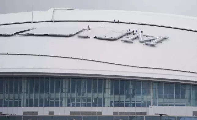 A crew covers the final visible signage atop the roof of AT&amp;T Stadium, which will be named Dallas Stadium during the 2026 FIFA World Cup, as preparations continue at the venue ahead of the soccer tournament, Friday, June 5, 2026, in Arlington, Texas. (AP Photo/Julio Cortez)